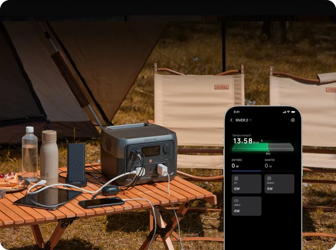 La RIVER 2 Max posée sur une table de camping au crépuscule, devant une tente, alimentant une tablette et un téléphone