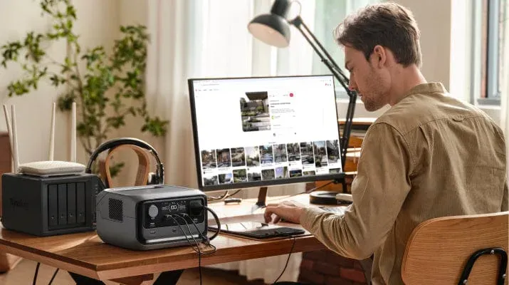 La RIVER 3 Plus posée sur un bureau, reliée à un écran, à un NAS quatre baies et à une box internet